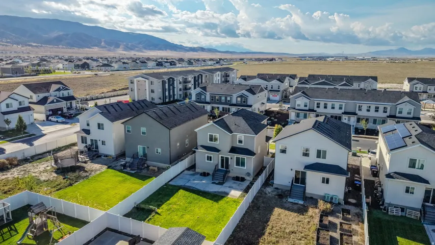 Expansive residential development featuring detached homes with fenced yards, multi-family structures, and mountain scenery