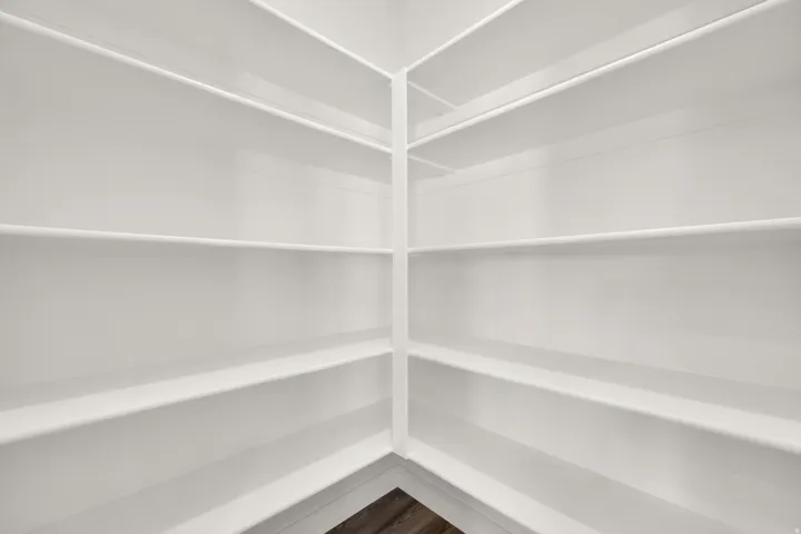 Built-in white shelving system with a corner configuration, offering extensive storage capacity