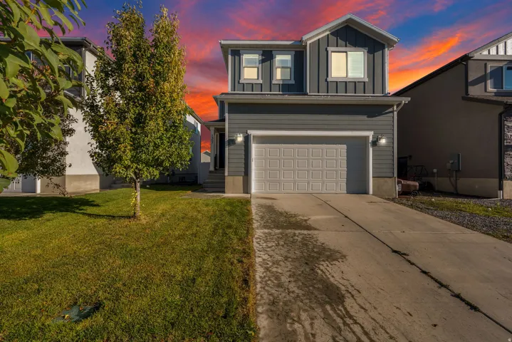 Two-story residence featuring grey horizontal siding, vertical siding accents, a two-car garage, and a concrete driveway