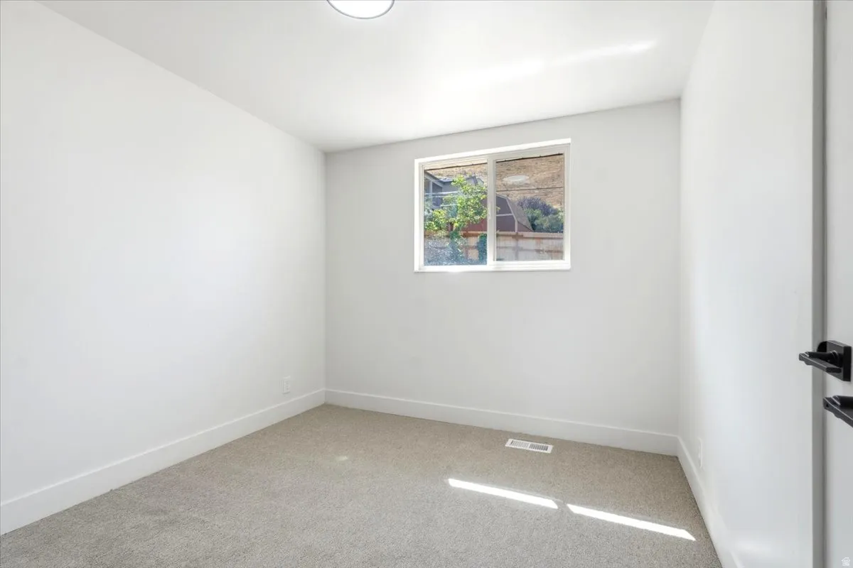 Neutral carpeting, white walls, and a single window with a white frame