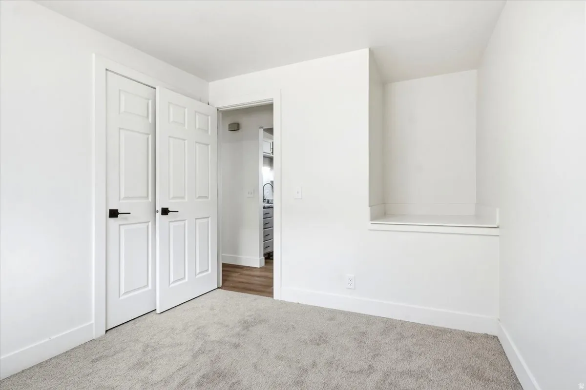 Plush carpet flooring, built-in shelving, panel doors with matte black hardware, and crisp white wall paint