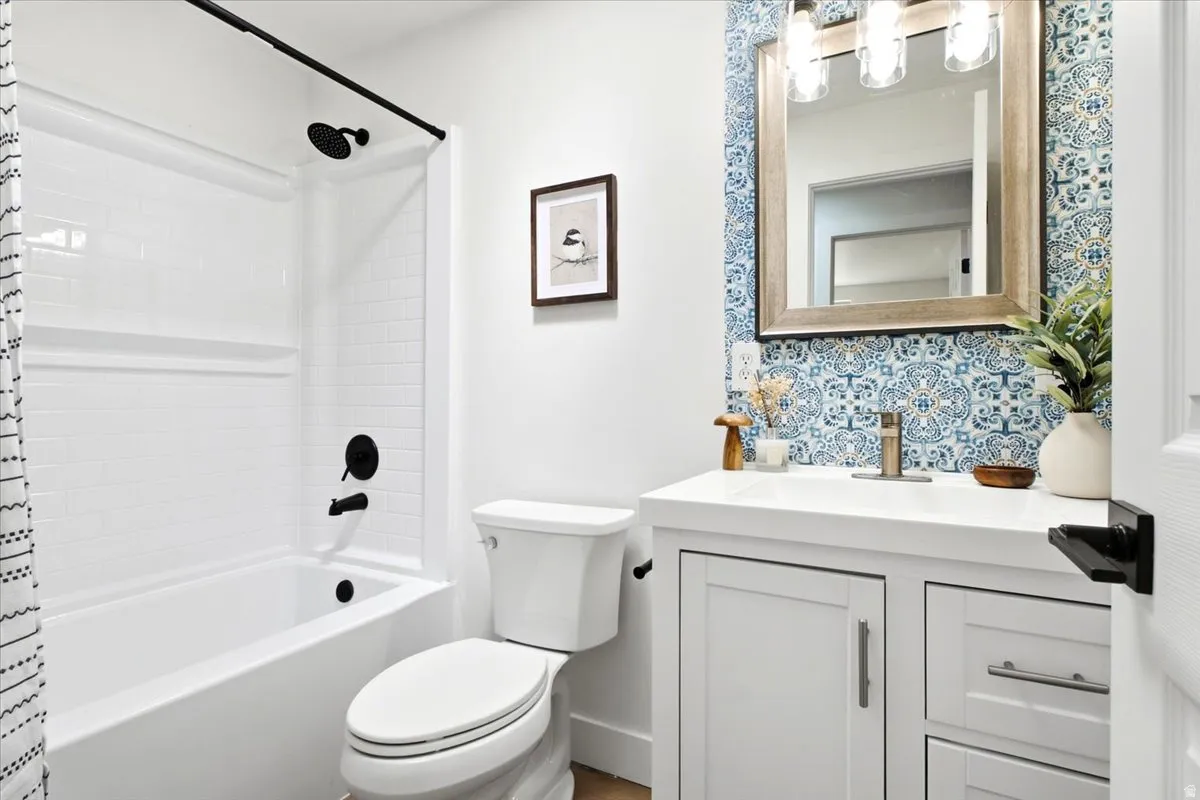 White vanity with an integrated sink, patterned tile backsplash, and a framed mirror