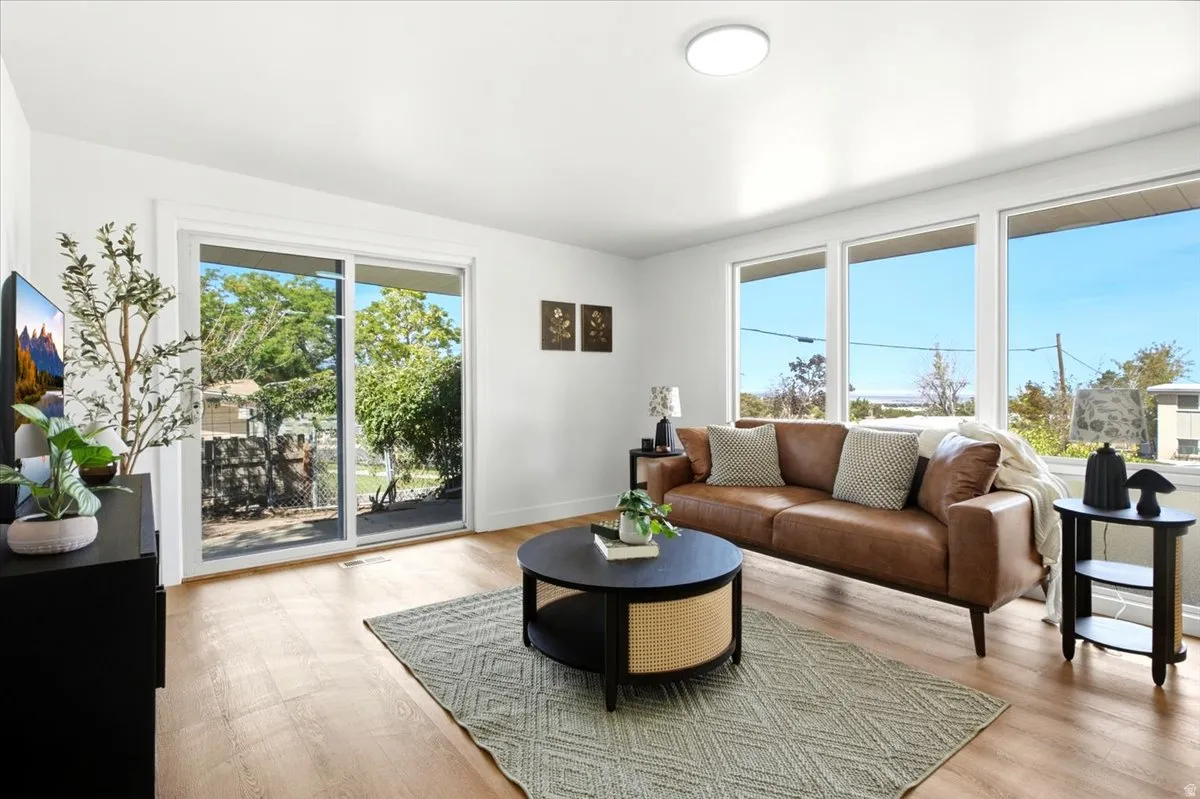 Wood-finish flooring, white walls, multiple large windows, and a sliding glass door