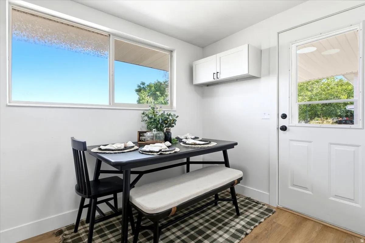 White wall-mounted cabinetry, a white door with a clear glass insert, and light wood-finish flooring