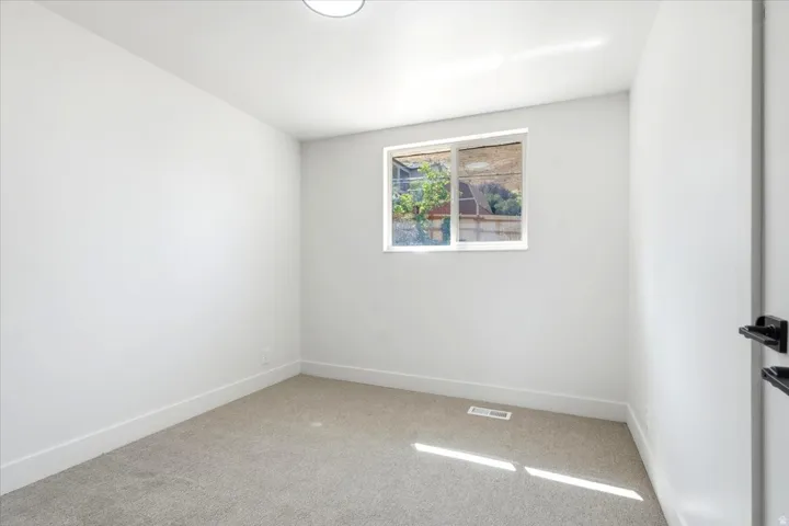 Neutral carpeting, white walls, and a single window with a white frame