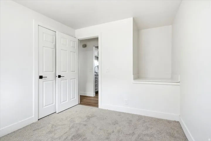 Plush carpet flooring, built-in shelving, panel doors with matte black hardware, and crisp white wall paint