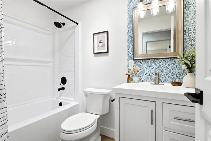 White vanity with an integrated sink, patterned tile backsplash, and a framed mirror