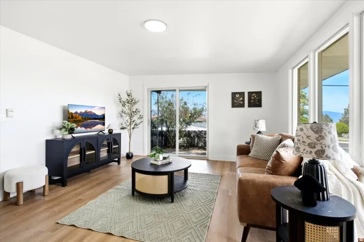 Wood-finish flooring throughout, multiple large windows, and a sliding glass door