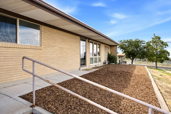 Brick exterior with multiple windows, covered entryway, and a sloped walkway with a handrail