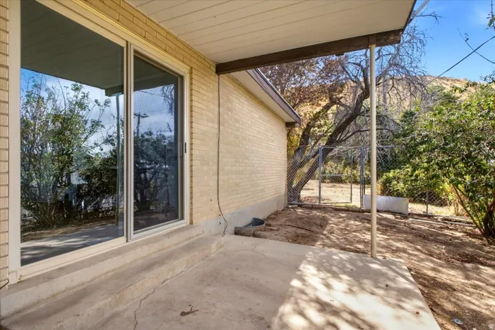 Concrete patio space featuring a partial overhead covering, brick exterior, and sliding glass door access
