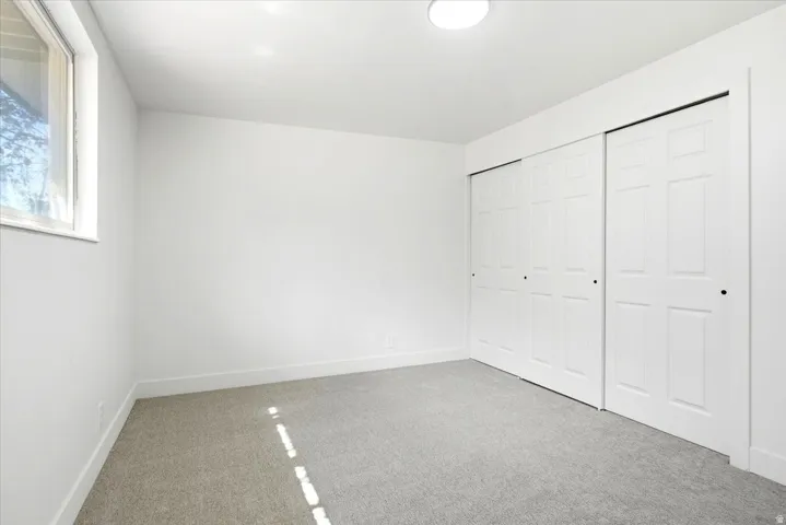 White walls, gray carpeting, and a window with white trim