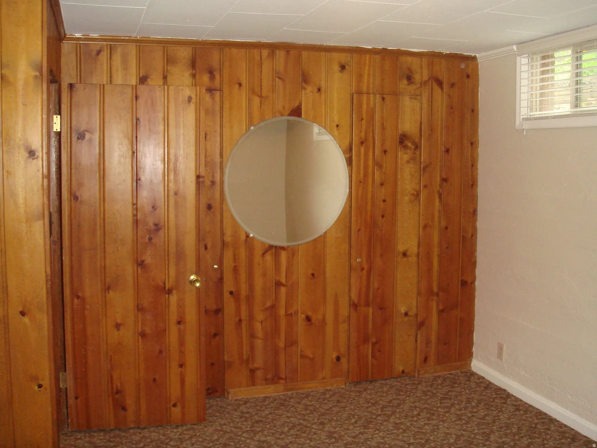 Wood-paneled wall with a circular mirror