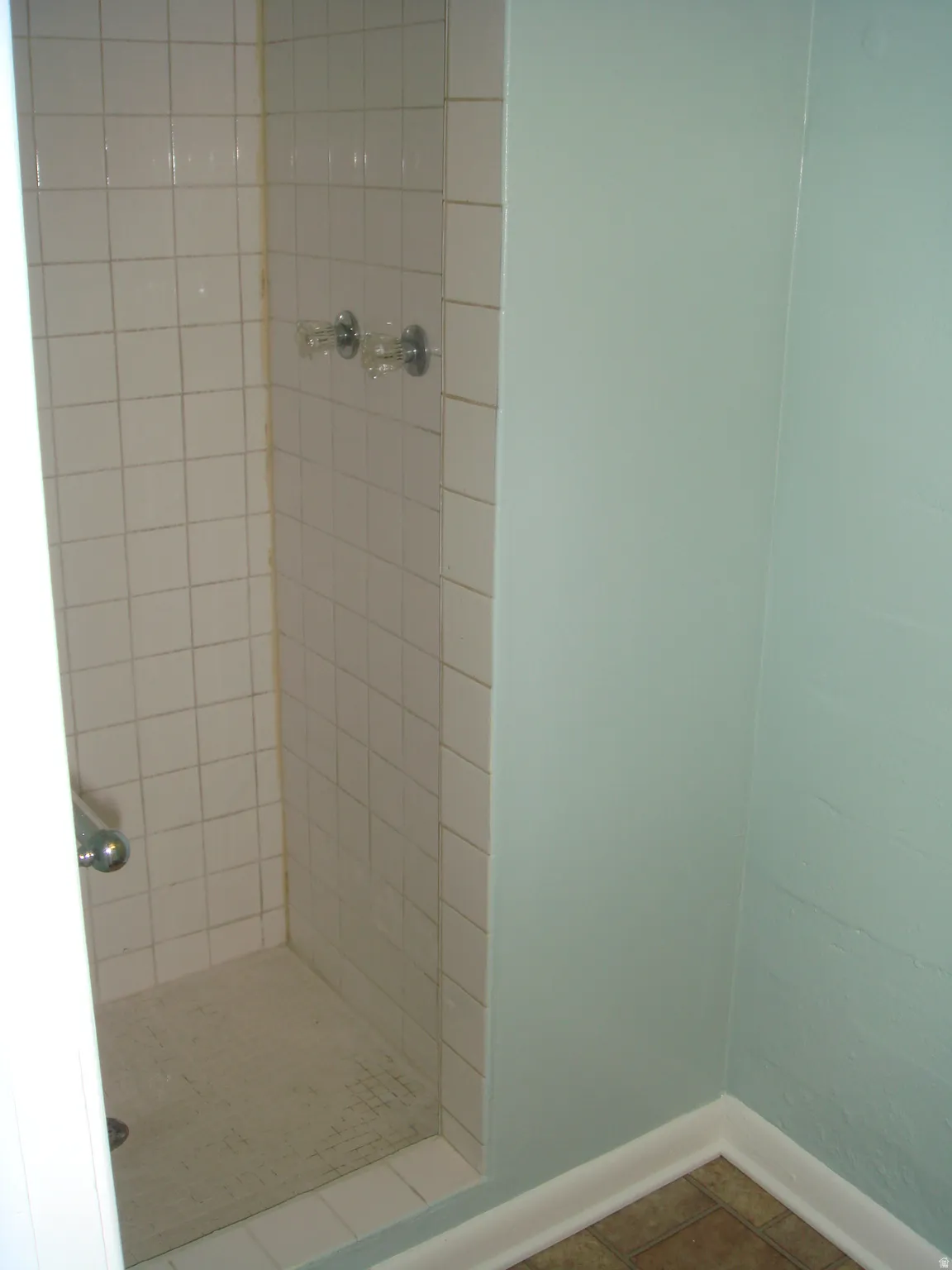 677 Shower stall with white tile surround and integrated floor, chrome fixtures, and a grab bar