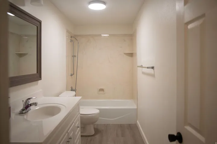 Bathroom featuring a white vanity with integrated sink, chrome faucet, framed mirror, and a shower/tub combination with a light-toned surround