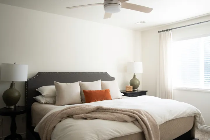 Primary suite featuring a ceiling fan with integrated lighting, a window with blinds, and white wall finishes