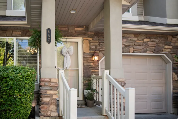Stone veneer exterior with a concrete entry and white railing