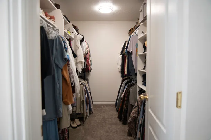 Primary walk-in closet featuring built-in shelving, hanging rods, and recessed lighting