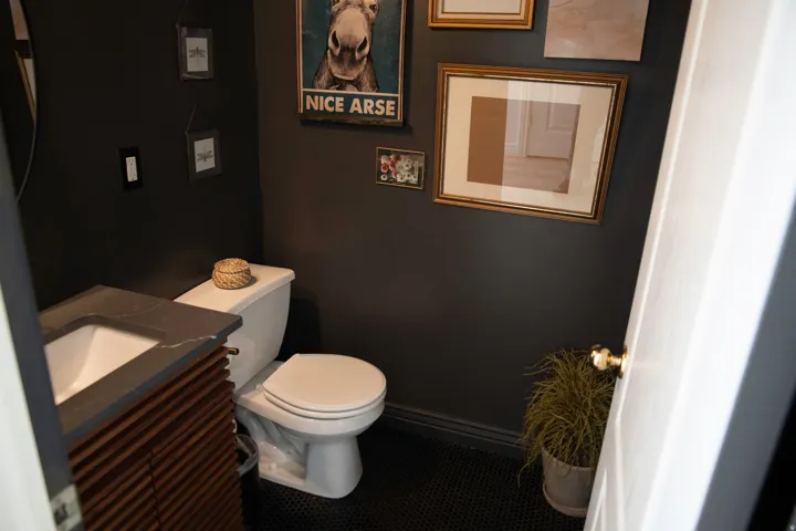 Wall-mounted vanity with a stone-finish countertop and integrated sink, white toilet, and dark hexagonal tile flooring
