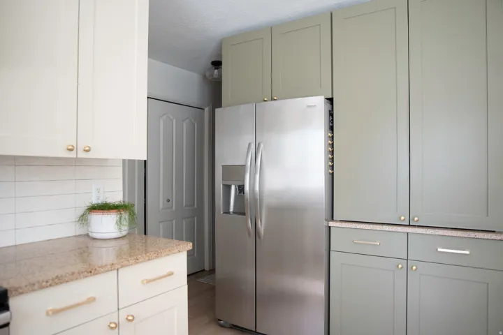 Modern cabinetry with mixed finishes and hardware, stainless steel side-by-side refrigerator, speckled countertop, and subway tile backsplash