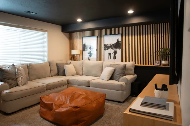 Recessed lighting, wood-slat accent wall, built-in shelving, light-toned carpeting, and a window with blinds