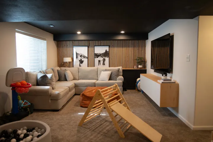 Recessed lighting, wood-slat accent wall, built-in shelving, window with blinds, wall-mounted media console
