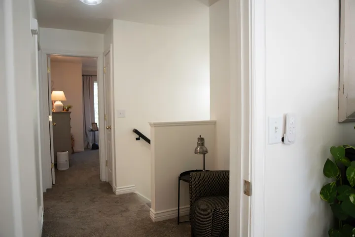 Second floor hallway with white interior walls with recessed lighting and neutral carpet flooring
