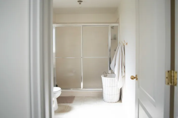 Primary suite bathroom featuring a large shower enclosure with frosted glass panels, a white toilet, and light-toned tile flooring