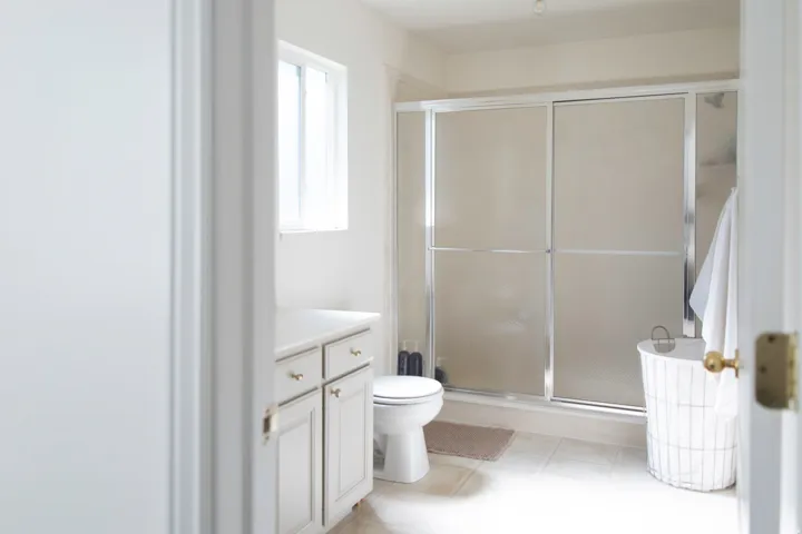 En-suite bathroom featuring a window, vanity with cabinet storage, toilet, and a shower with frosted glass doors