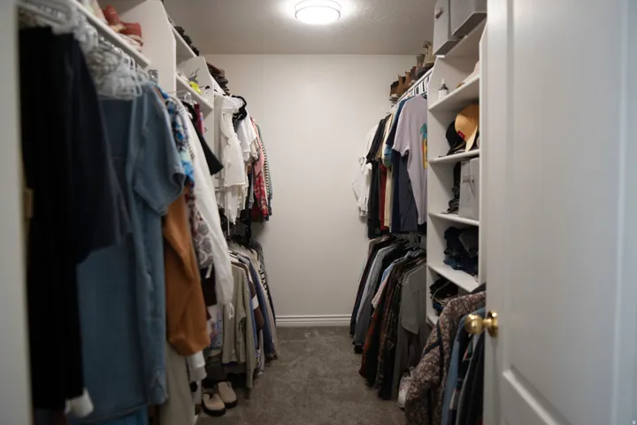 Primary suite walk-in closet featuring built-in shelving, hanging rods, and carpet flooring