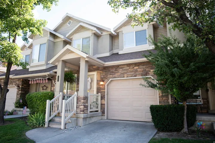 Exterior showcasing a covered entry, stone veneer accents, and an attached two-car garage