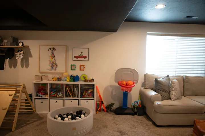 Recessed ceiling lighting, dark ceiling, light-colored walls, carpeted flooring, window with horizontal blinds