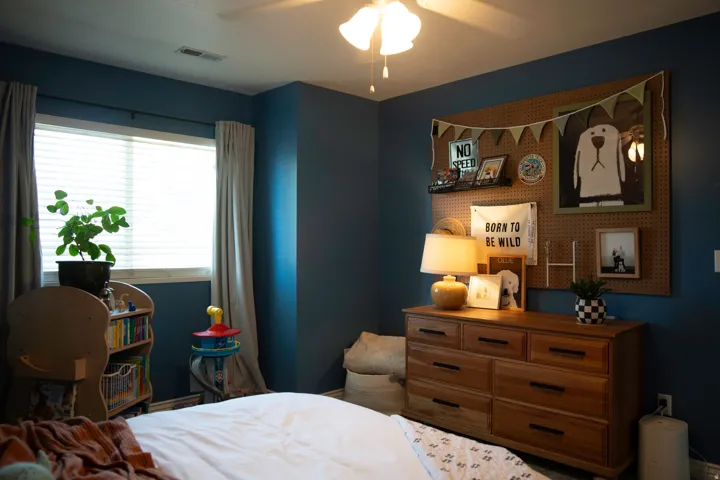 Recessed window with white blinds and drapes, ceiling-mounted light fixture, and deep blue wall color
