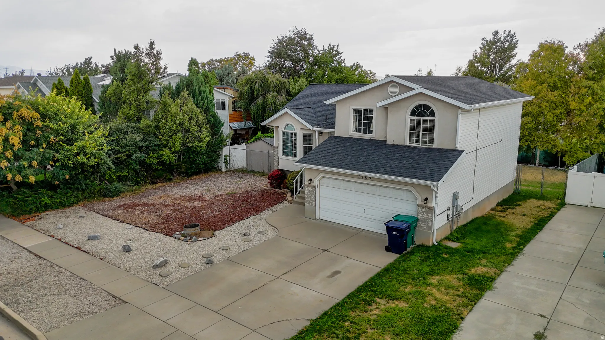 Two-story residence with a two-car garage, stucco and siding exterior, and an arched window