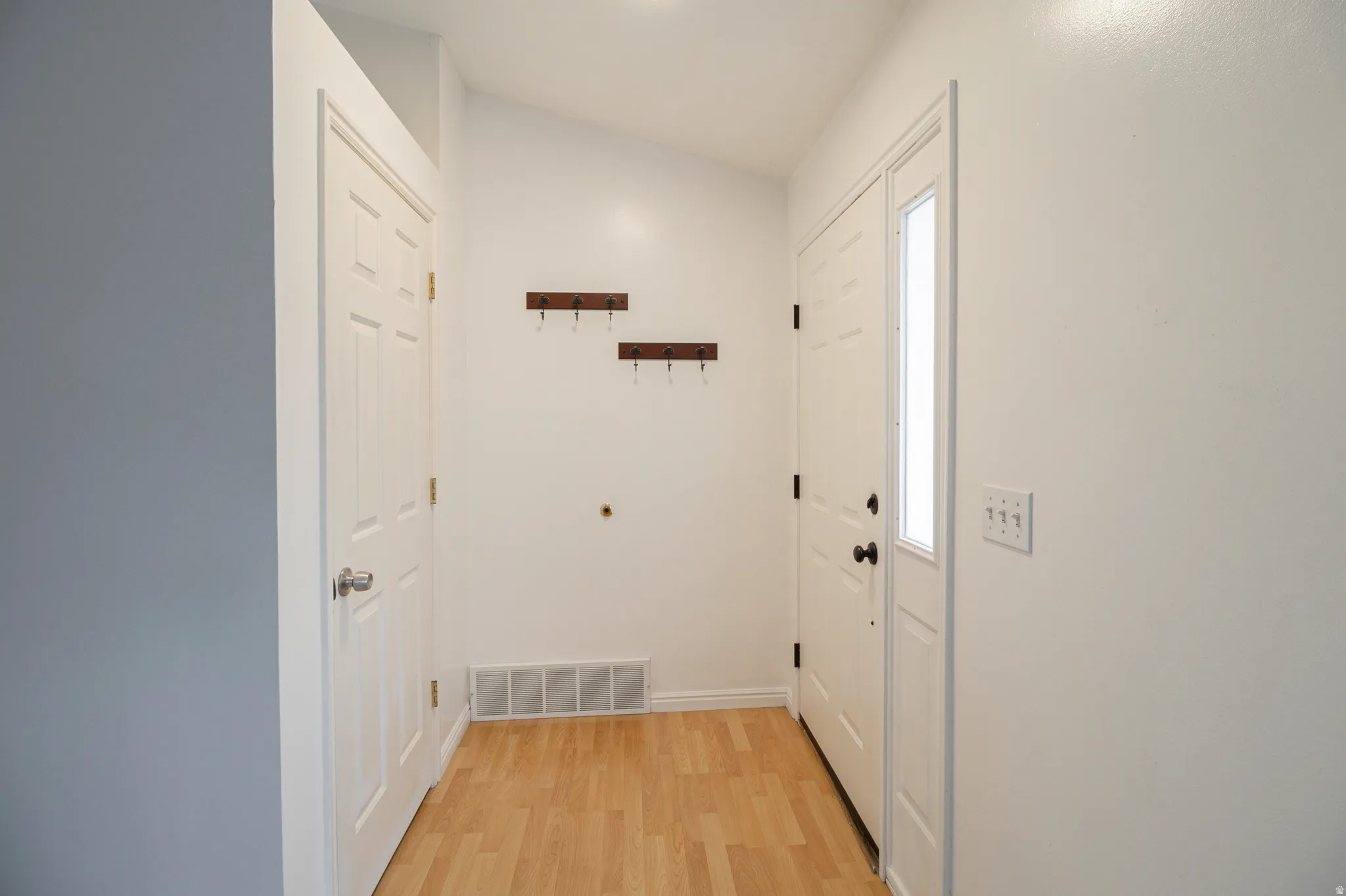 Entryway featuring wood-finish flooring, white panel doors, and a side-lite entry door