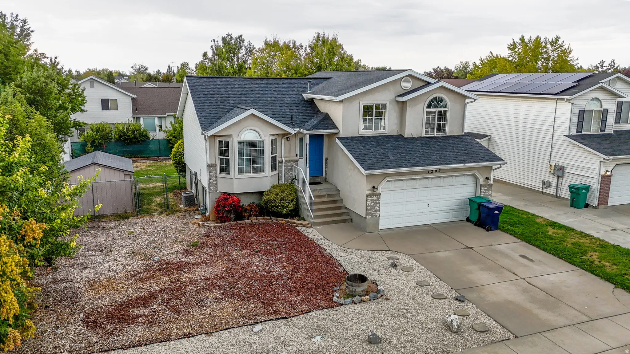 Two-story residence featuring a bay window, attached garage, and a shed