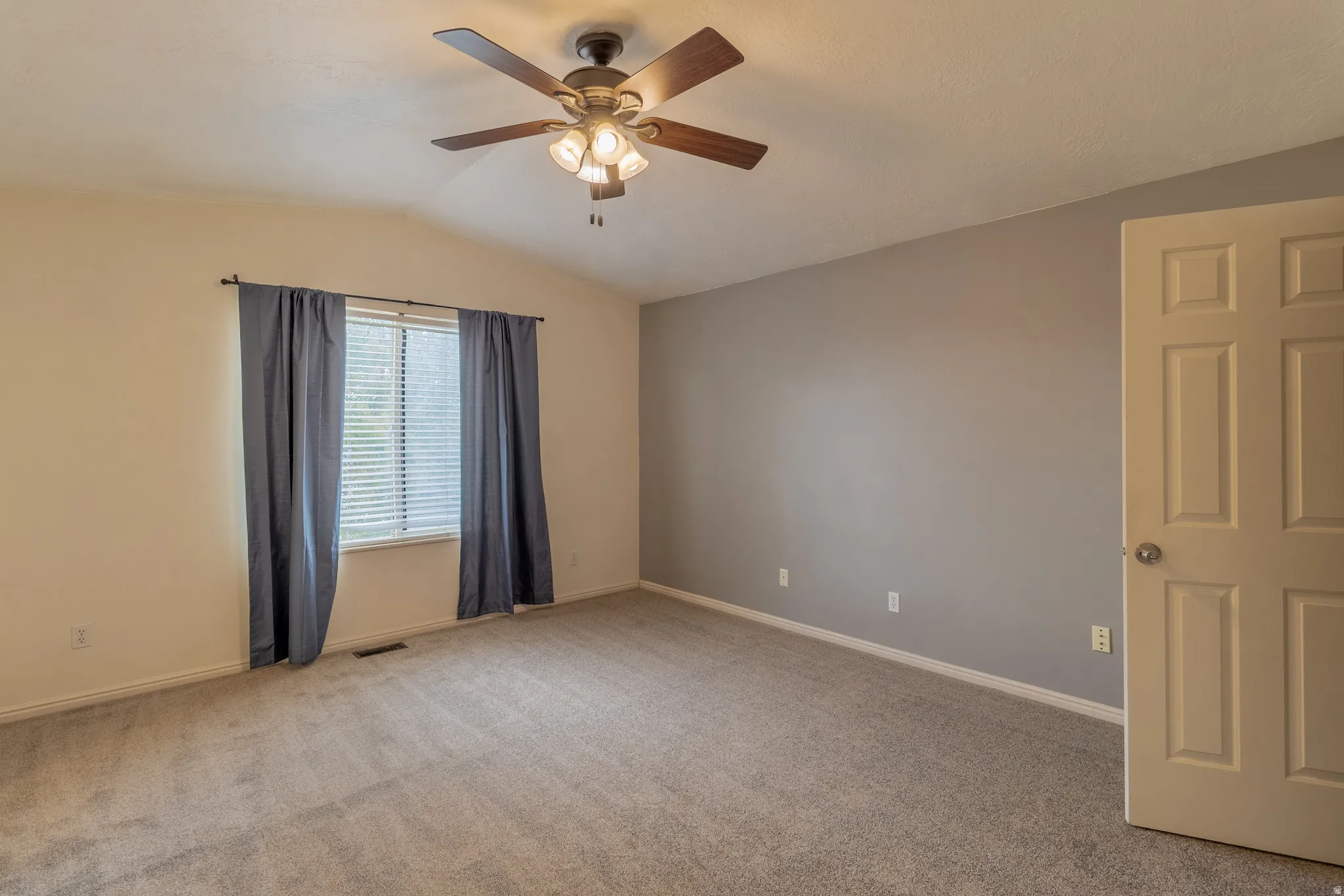 Vaulted ceiling with an attached ceiling fan, neutral wall colors, and a paneled interior door