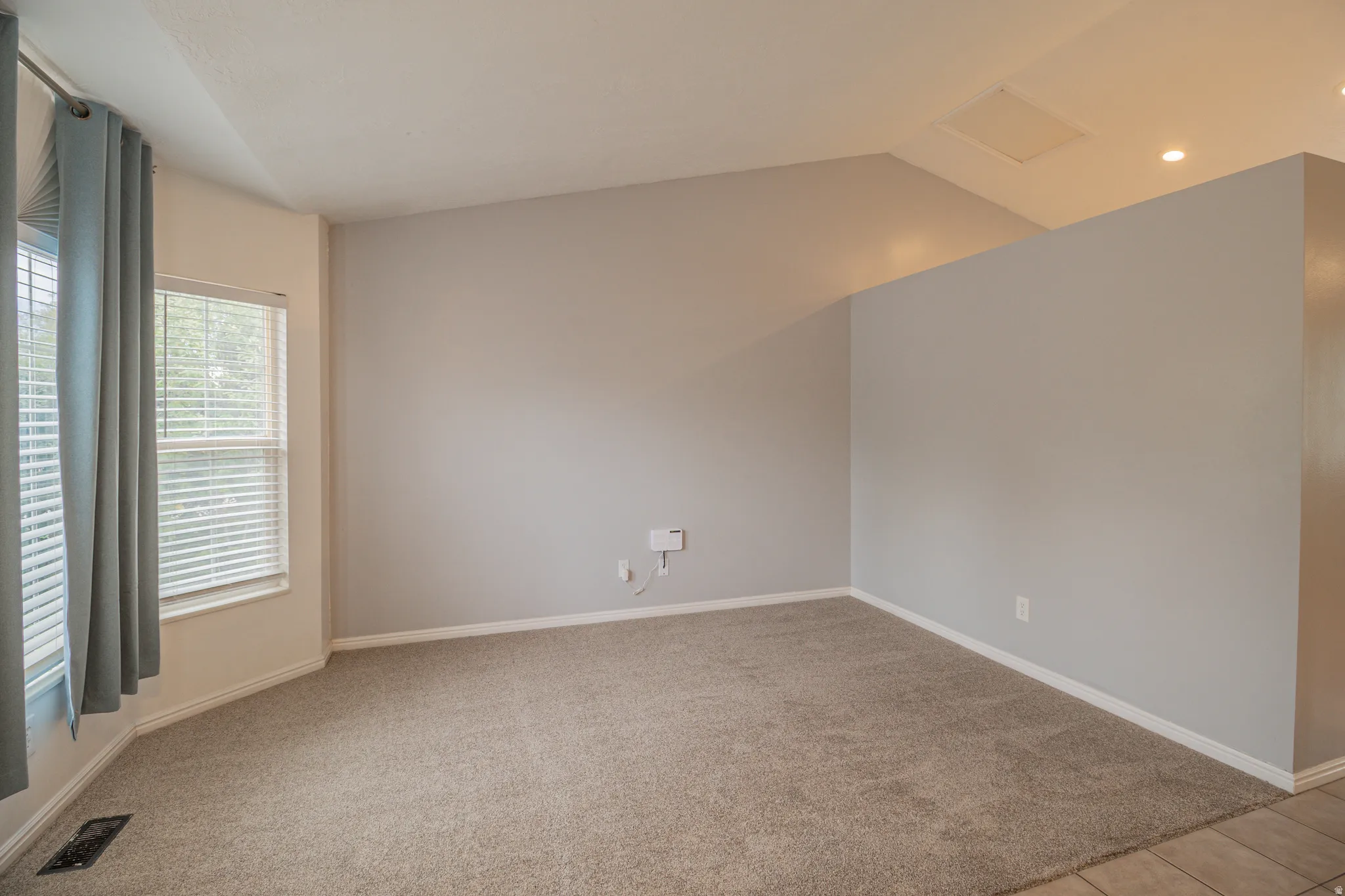 Carpeted living area with vaulted ceilings, recessed lighting, and ample natural light from multiple windows