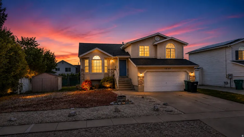 Two-story residence featuring a stone-accented facade, attached garage, and a gravel front yard with mature landscaping