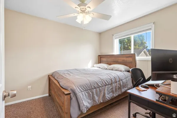 Carpeted flooring, ceiling fan with integrated lighting, and a window with blinds