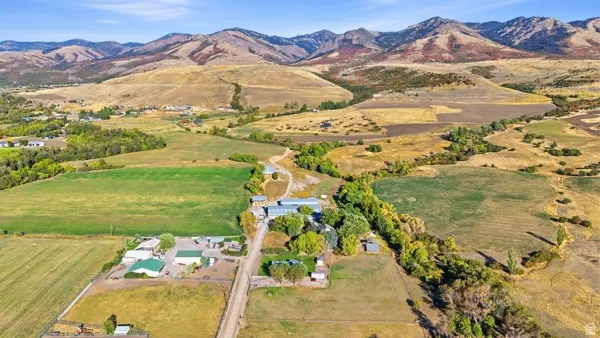 Expansive property featuring diverse terrain, multiple structures, and distant mountains
