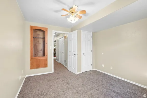 Carpeted flooring with light-toned walls and a built-in wood cabinet