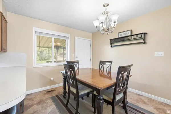 Tile flooring, neutral wall paint, white trim, white paneled door, and a multi-light chandelier