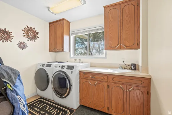 Laundry area featuring built-in wood cabinetry, a window with exterior visibility, a countertop with an integrated sink, and an overhead light fixture