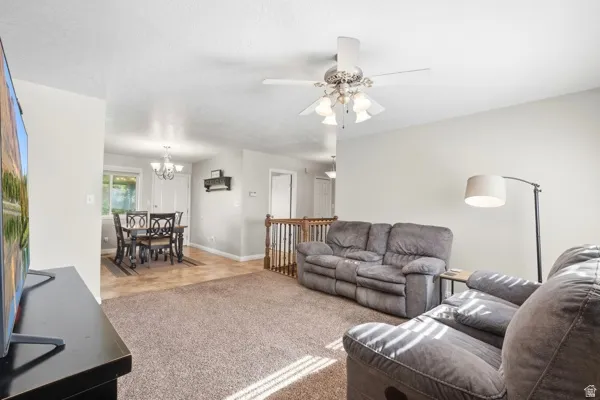 Open-concept living area with carpet flooring and ceiling fan