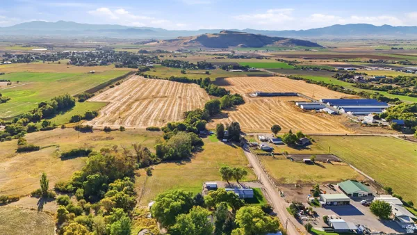 Expansive rural landscape featuring agricultural fields, scattered structures, and distant mountains