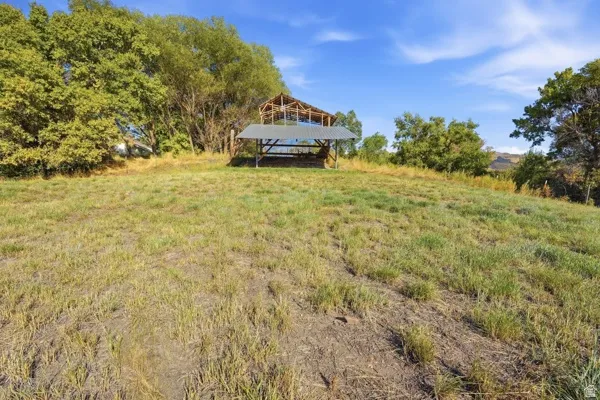 Expansive grassy terrain with a distant structural framework and a covered outdoor area