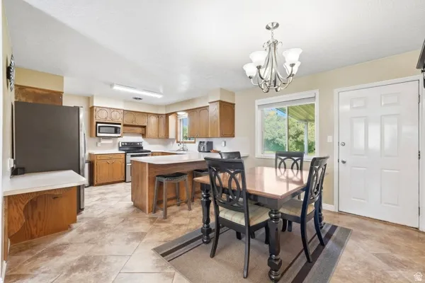 Kitchen featuring wood cabinetry, an island with seating, stainless steel appliances, and tile flooring