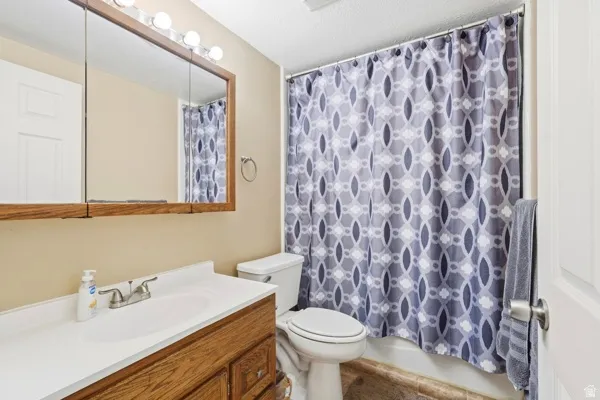 Vanity with integrated sink, wood-finish cabinetry, and wall-mounted mirror with integrated lighting
