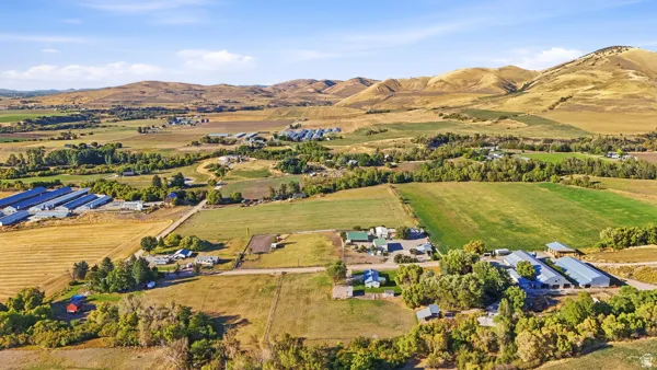 Expansive rural property featuring multiple agricultural structures, cultivated fields, and surrounding natural landscapes