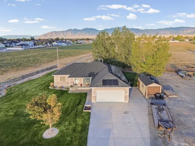 Single-story residence featuring a two-car garage, concrete driveway, and a shingled roof with integrated solar panels